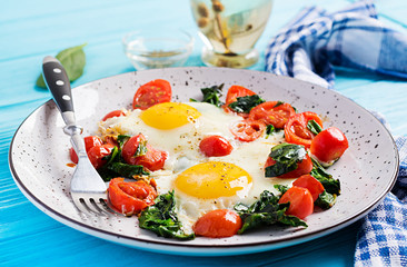 Plate with a keto diet food. Fried egg, spinach, and tomatoes. Keto, paleo breakfast.