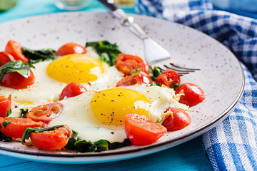 Plate with a keto diet food. Fried egg, spinach, and tomatoes. Keto, paleo breakfast.