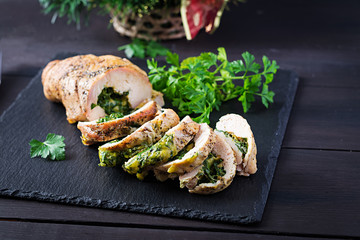 Roasted sliced Christmas roll of turkey with spinach and cheese on dark rustic background.  Festival food.