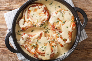 boneless pork chops served in creamy wine sauce with herbs close-up in a pan. Horizontal top view