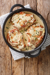 Delicious pork chops stewed in a creamy wine sauce with herbs close-up in a pan. Vertical top view