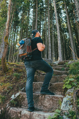 Naklejka premium man with backpack walking by stone stairs that leads to the forest
