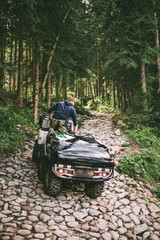 man on all-terrain vehicle ride by stone trail in forest