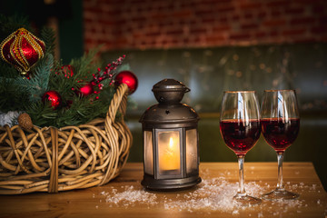 Two red wine glass on wooden loft table decorated christmas garland and lantern