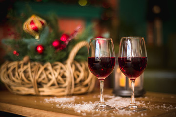 Two red wine glass on wooden loft table decorated christmas garland and lantern