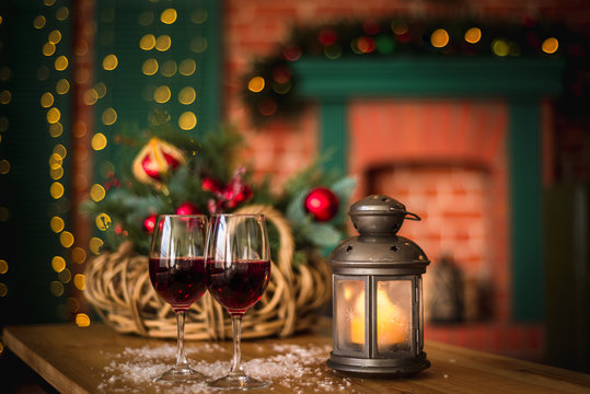 Two red wine glass on wooden loft table decorated christmas garland and lantern