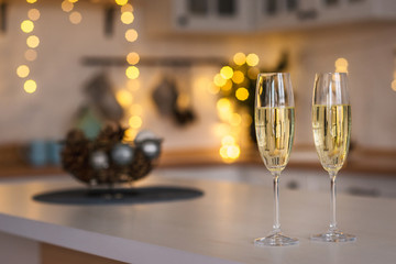 Two champagne glasses stand on kitchen table in christmas decorated interior