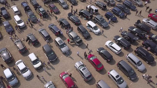 Aerial top view of many cars parked and people customers walking on car market or parking lot.
