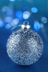 Christmas and New Year winter festive background.Blue christmas ball with beads on blue glitter with blurry bokeh background.Phone christmas wallpaper