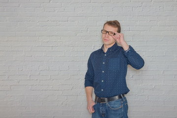 man in a shirt gestures to the wall of white brick a place for a label