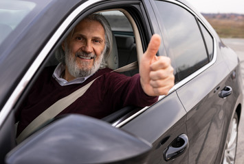 Senior driver is showing tumb up 