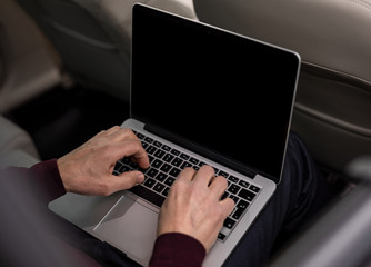 Close up of senior man working on computer while driving in the car