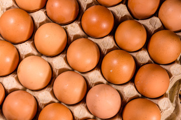 Pile of the hen eggs in paper tray on wooden table. Top view