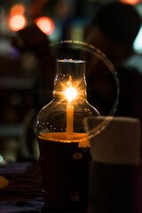 A candle lit in a glass lamp.