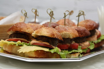 Sandwiches with cheese and lettuce. Burgers with a toothpick skewer on a plate