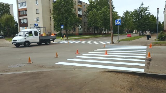 Workers apply by paint horizontal road marking zebra for Pedestrian crossing on crossroads in city street asphalt