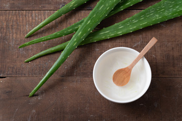 Cut aloe vera stem and gel in wooden bowl on wooden background