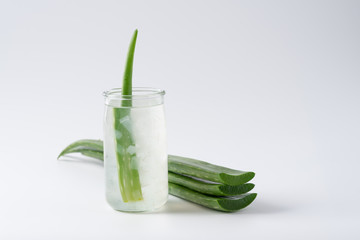 Cut aloe vera stem and gel in wooden bowl on white background