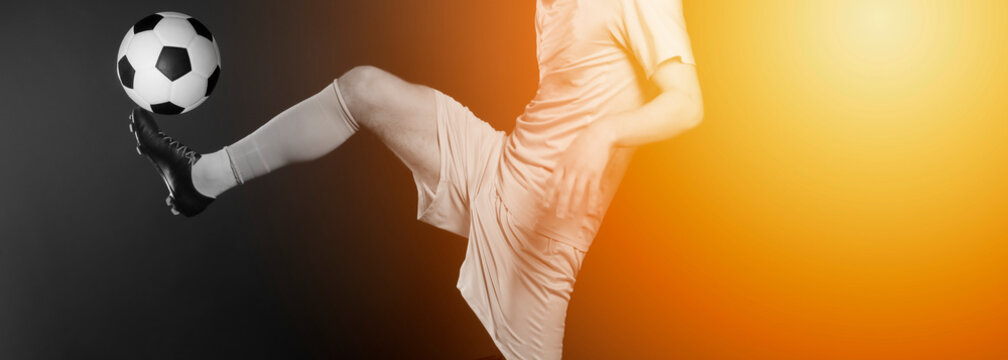 Close up legs and soccer shoe of football player in action kicking ball isolated on black background.Yellow filter