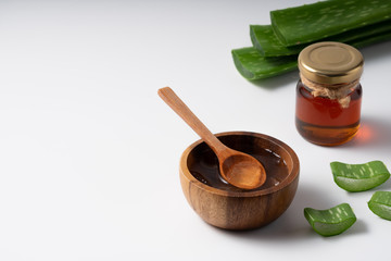 Cut aloe vera stem and gel in wooden bowl on white background