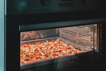 Big rectangular pizza cooks in the built-in electric oven. White kitchen. Culinary. Food....