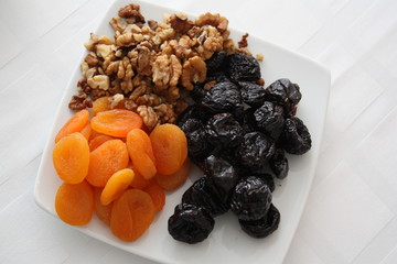 Walnut, prunes, dried apricots in a white plate on the table