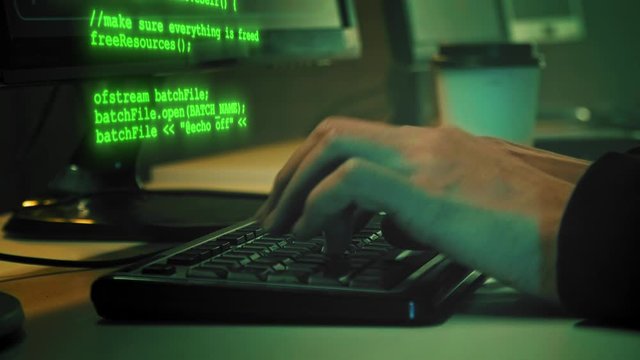 Сlose-up of hacker hands while green code characters fly out of the keyboard in the dark office room. 4K (UHD)