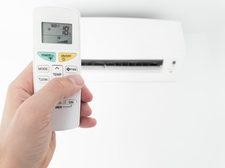 Modern airconditioner unit with a hand holding a remote.