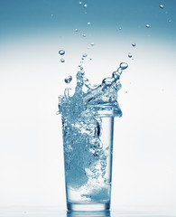 one glass of water with splash from falling ice cube, white background, isolated object