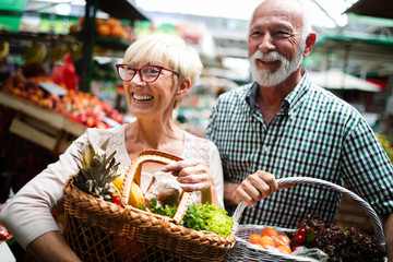 Mature shopping couple with basket on the market. Healthy diet.