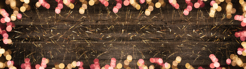 Festive background panorama banner long - Pink and yellow bokeh lights and golden glitter on dark...