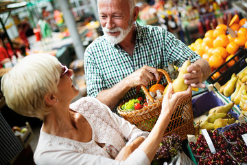 Mature couple shopping vegetables and fruits on the market. Healthy diet.