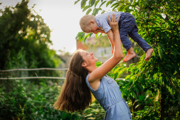 Fototapeta premium Happy beautiful mother with her son in her arms in garden