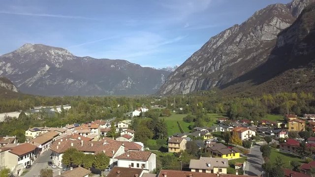 Aerial view of a small historic town Venzone in Northern Italy with red tiled roofs of old buildings and majestic Alps mountains.