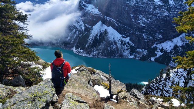 Man sitting on a rock looking above the Lake Louise. Nice viewpoint in Banff Nationalpark, Canda