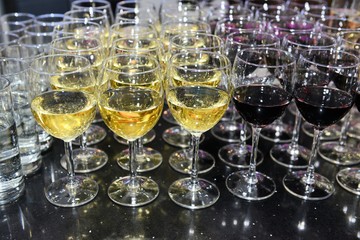 Rows of full champagne, sparkling wine and red wine glasses. Dining, drink. Catering service concept.