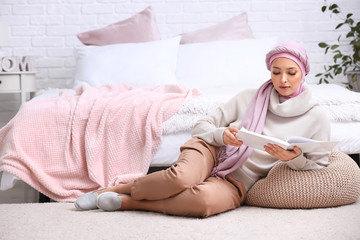 Portrait of beautiful Muslim woman reading book in bedroom