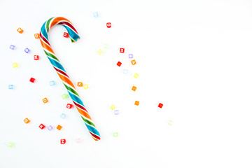 Colorful festive Lollipop and small cube letters on white background selective focus top view