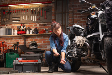 Plakat Woman mechanic fixing motorcycle in garage