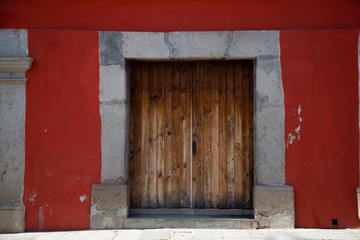 Old door in colonial city with red wall- Antigua Guatemala
