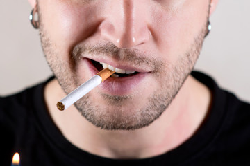 lower half of the face of an unshaven man who is about to light a cigarette