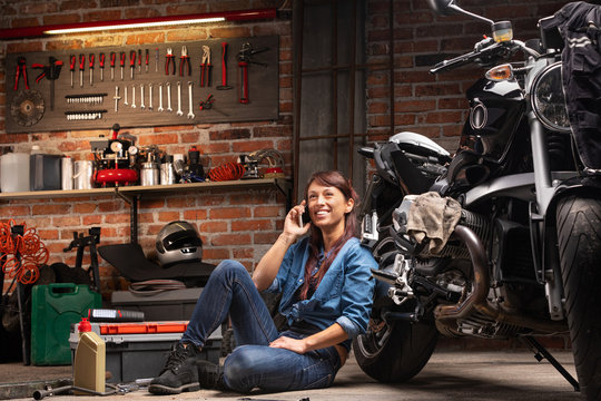 Female biker relaxing alongside her vintage bike