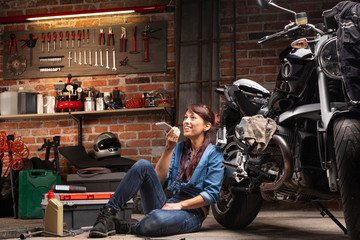 Fototapeta na wymiar Female mechanic relaxing in a motorbike workshop