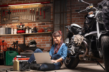 Naklejka na ściany i meble Young woman working in a vintage bike workshop