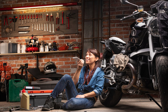 Female mechanic relaxing in a motorbike workshop