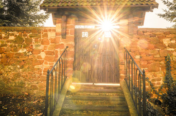 Old wooden gate with sun rays shining through. Concept of gate to happiness or heaven