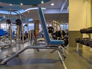 Fototapeta na wymiar Bench for weight lifting and bodybuilding in an indoor modern empty gym with a lot of equipment for healthy lifestyle and recreation