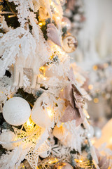 Close up a Christmas tree lights glittering at night. New Year fir tree with decorations and illumination. Xmas tree decorations background. Many large golden balls on fir tree New Year and Christmas