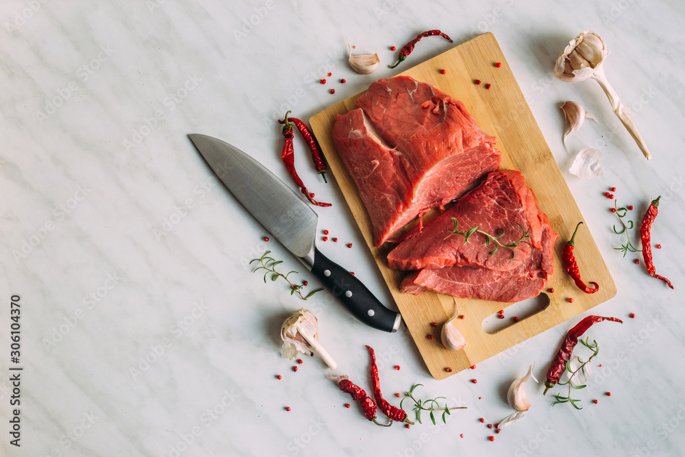 Wall mural Fresh pork raw fillet on wooden board. Red beef meat on a cutting board.