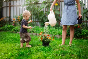 Fotobehang Mom and boy child water the garden together joke © natalialeb